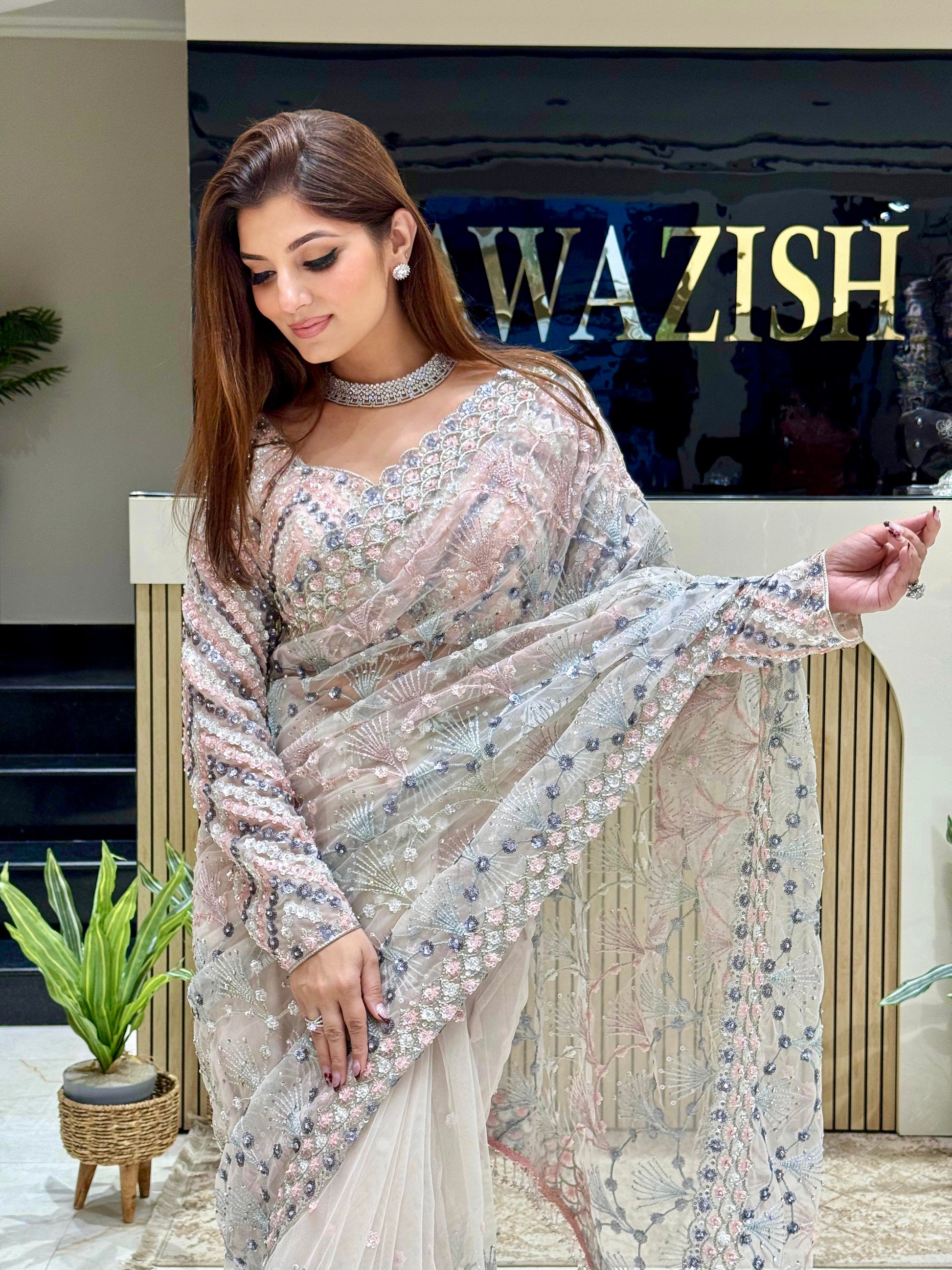 Stylish drape of silver net saree with delicate handcrafted detailing, paired with a couture-style embellished blouse for luxurious Indian wedding looks.