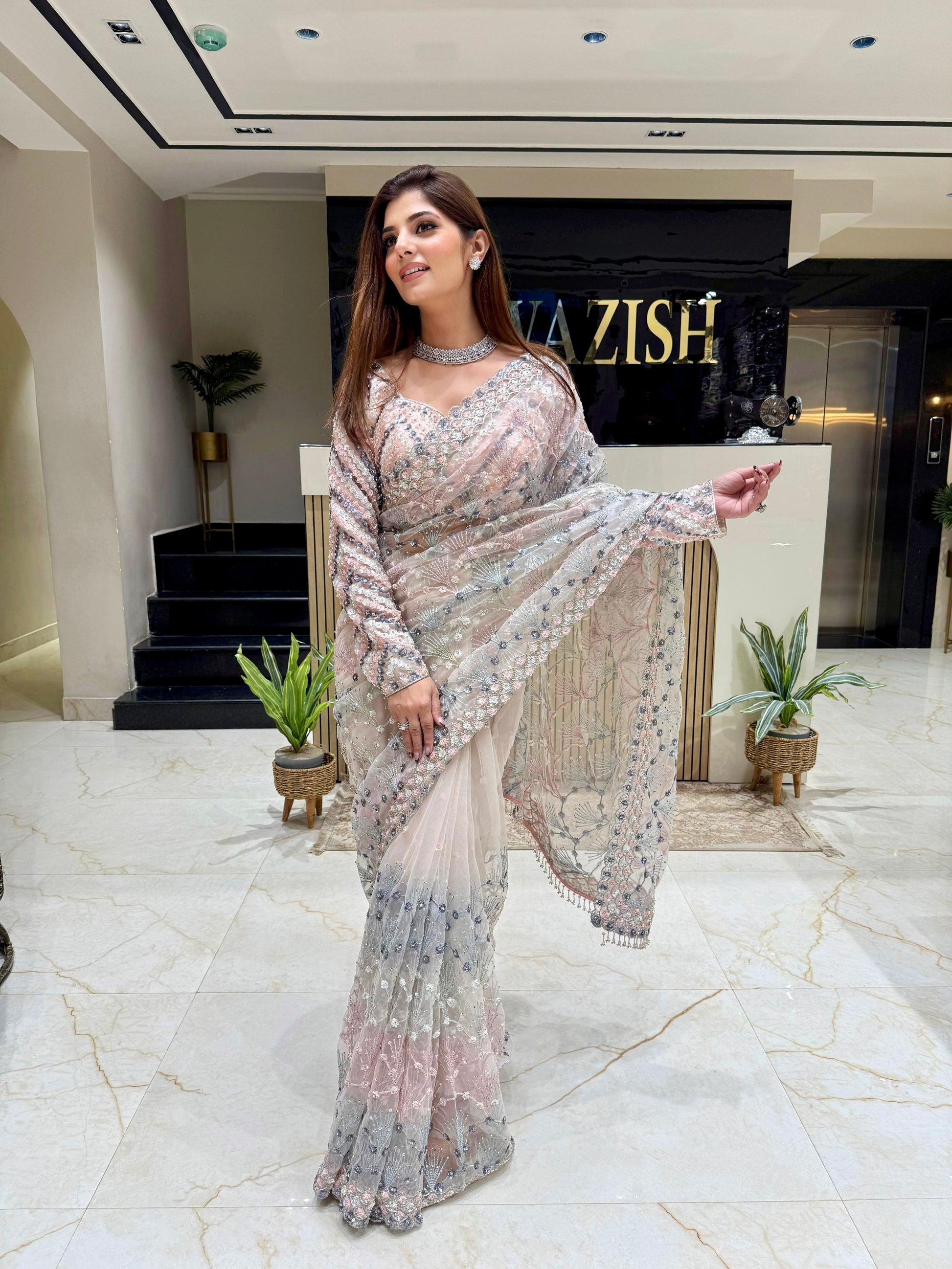 Elegant silver net saree with all-over hand embellishments, styled with a matching heavily embroidered designer blouse for bridal and evening wear.
