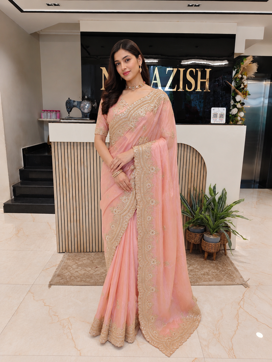 Woman in a pink saree standing in a modern interior setting with 'Niazish' branding.