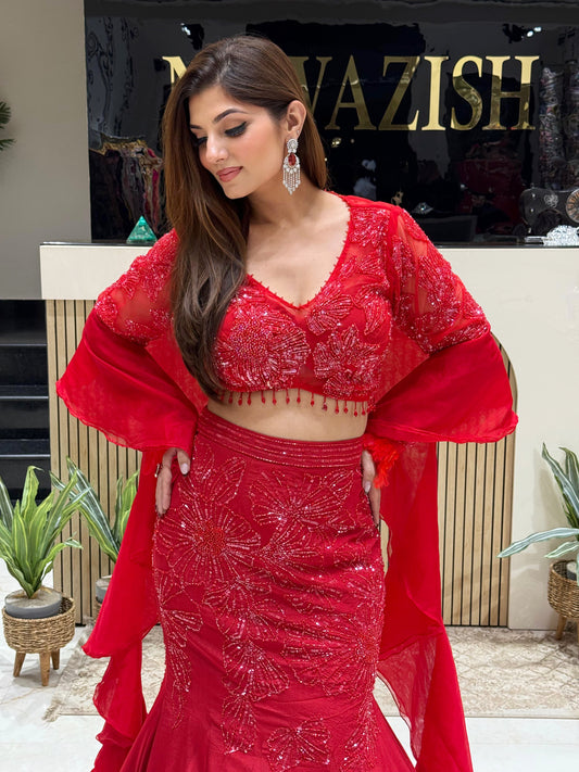 Elegant red bridal lehenga in fish-cut silhouette with intricate embroidery and dramatic ruffle dupatta.