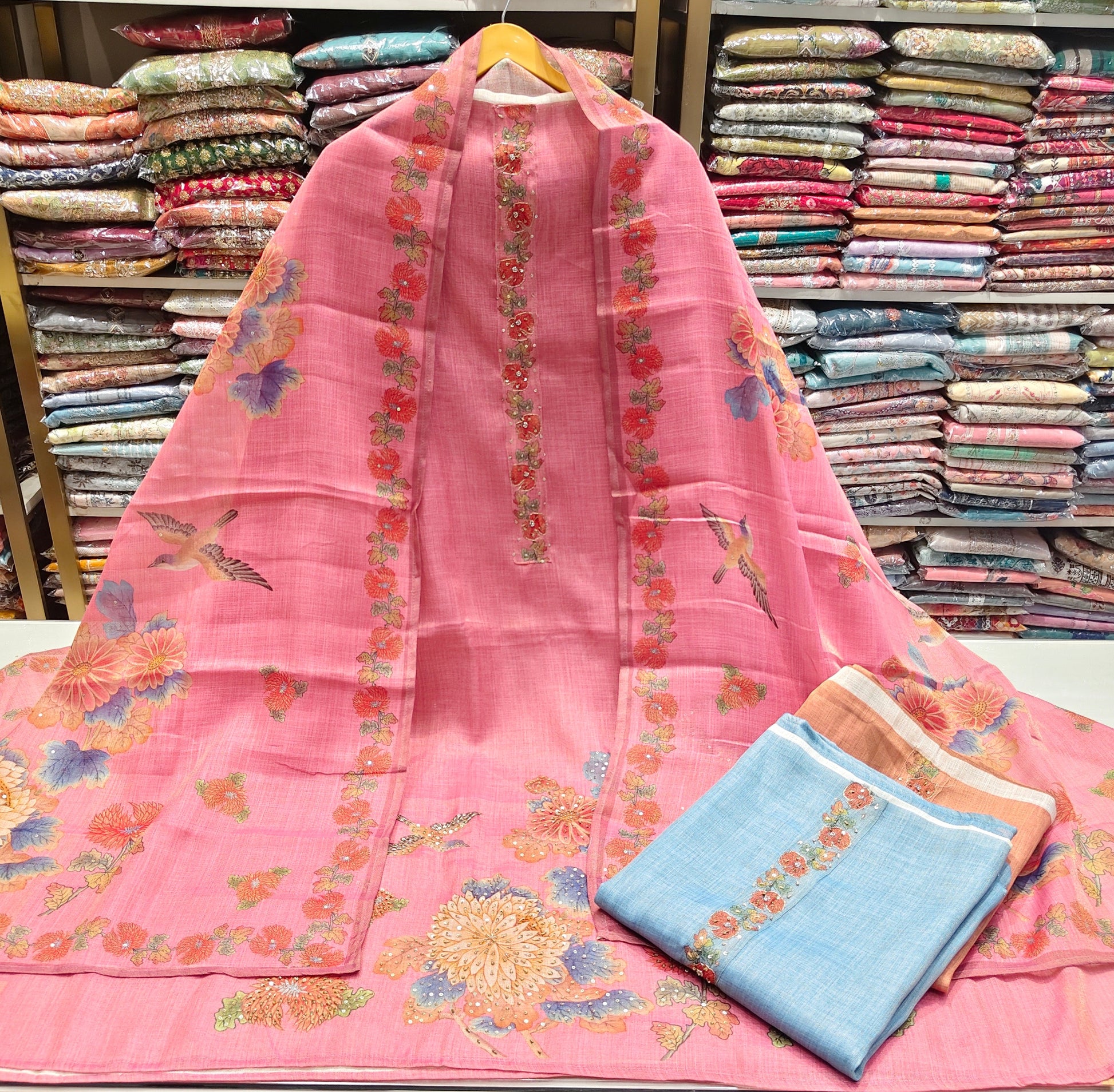 Pink embroidered fabric with a blue pocket on a table in a fabric store.