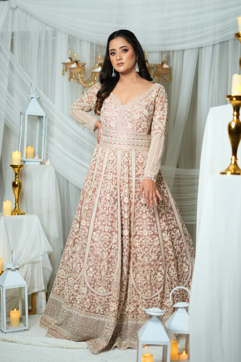 Elegant dusky peach bridal gown by Nawazish, featuring intricate white hand embroidery and embellishments. A luxurious handcrafted wedding gown perfect for modern Indian brides. Ideal for reception or engagement, with timeless ethnic charm and couture craftsmanship.