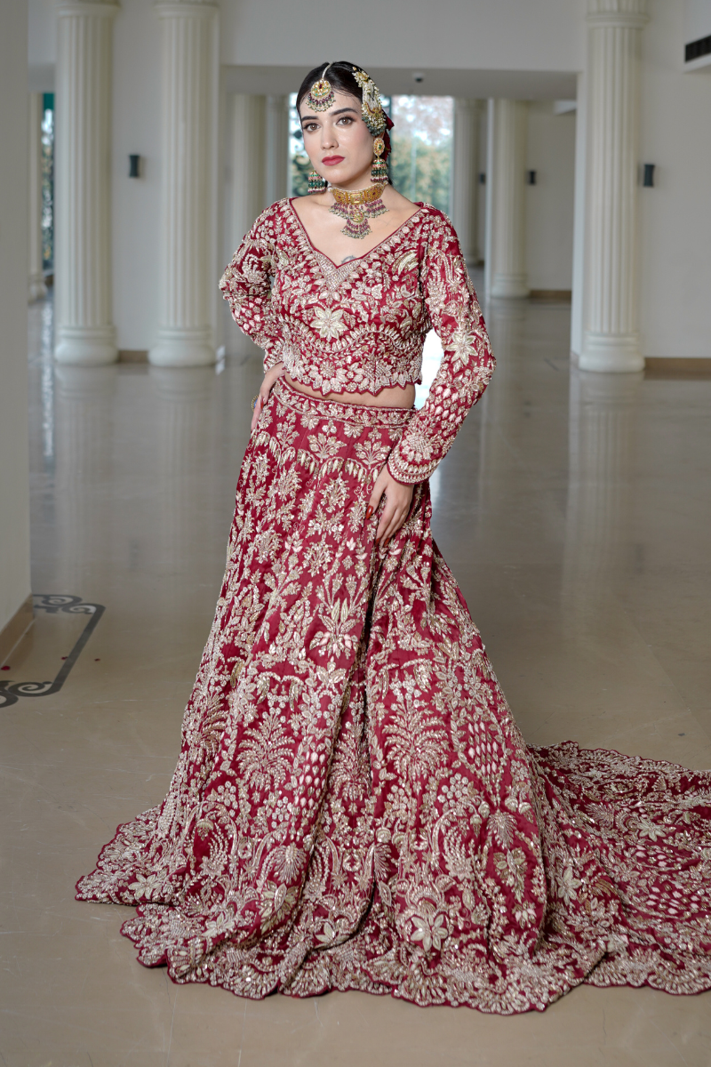 Majestic red bridal trail lehenga by Nawazish, handcrafted on rich organza fabric with intricate Zardozi and Dabka embroidery. Featuring a grand 8-feet-long trail, this lehenga is a true celebration of traditional Indian bridal couture. Ideal for classic brides seeking elegance, grandeur, and heritage craftsmanship.