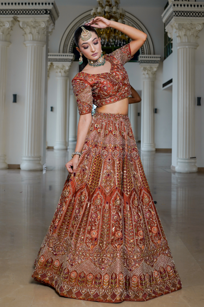 Exquisite rust-toned bridal gown by Nawazish, featuring the finest hand embroidery crafted for the modern Indian bride. Rich ethnic hues paired with intricate threadwork and traditional craftsmanship make it ideal for weddings, receptions, and bridal portraits steeped in heritage and elegance.