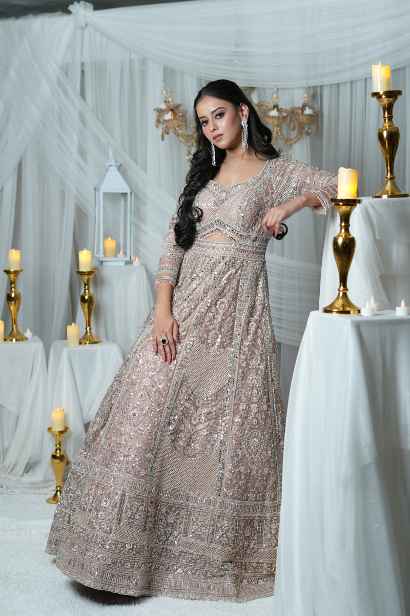 Stunning rose gold bridal gown by Nawazish, crafted on a delicate net base with intricate hand embroidery. Features luxurious pearl detailing and shimmering mirror work, making it the perfect couture ensemble for modern Indian brides. Ideal for weddings, receptions, and high-fashion bridal moments.